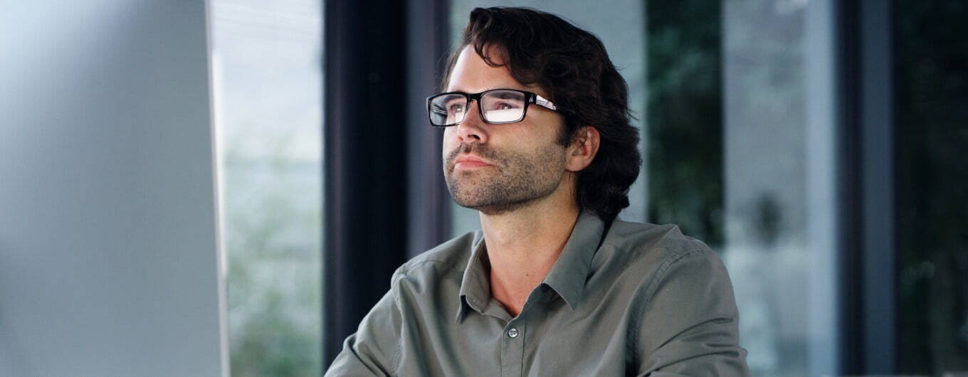 Man in glasses looking at a computer screen